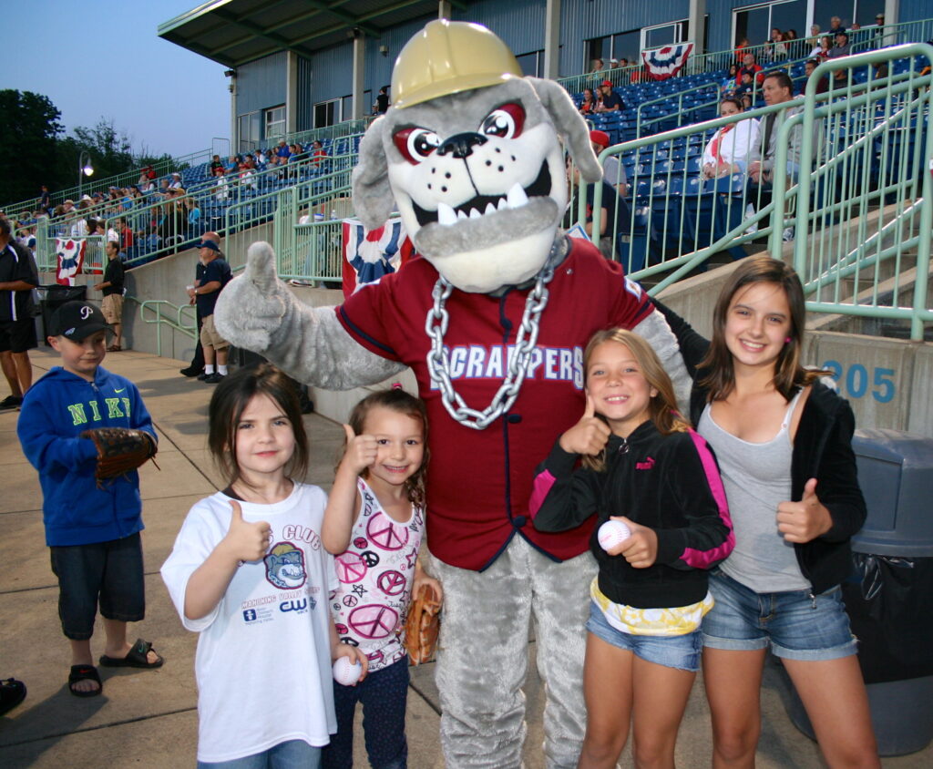 Scrappy posing for a photo with four smiling kids at a scrappers game