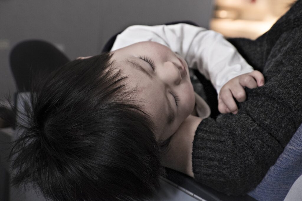 A sleeping child in the arms of a parent