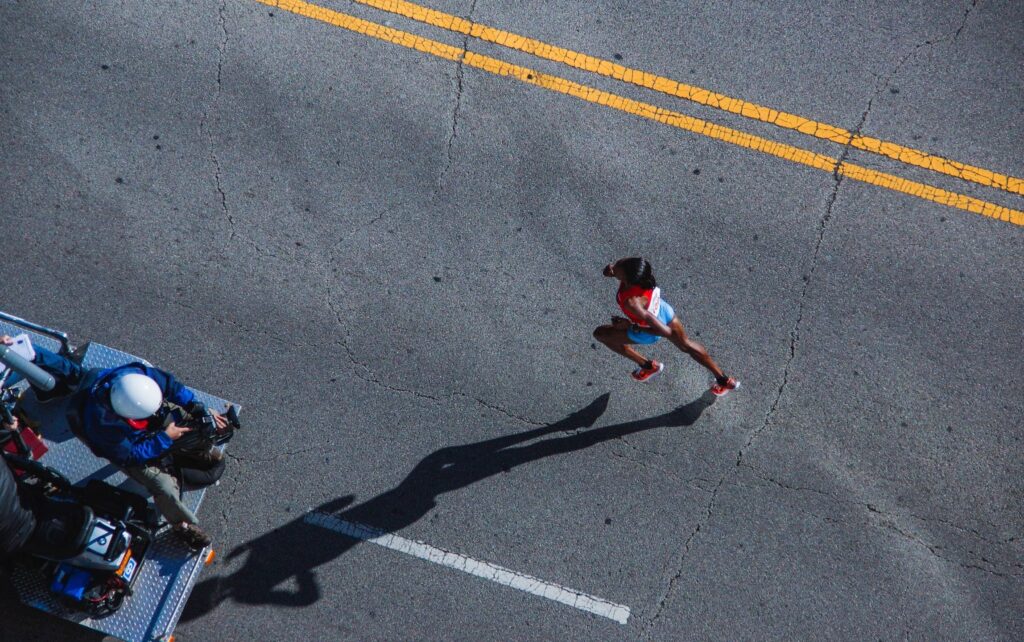a woman running in a road race while being filmed